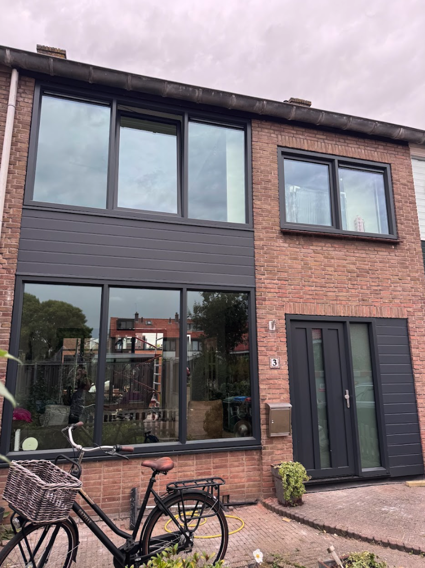 Rijtjeswoning met nieuwe donkere kozijnen na renovatie in Vierpolders