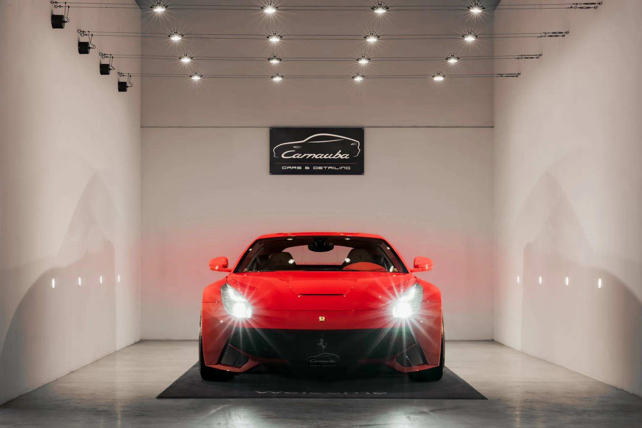 Rode Ferrari onder het Carnauba logo in de showroom van Carnauba Car Detailing