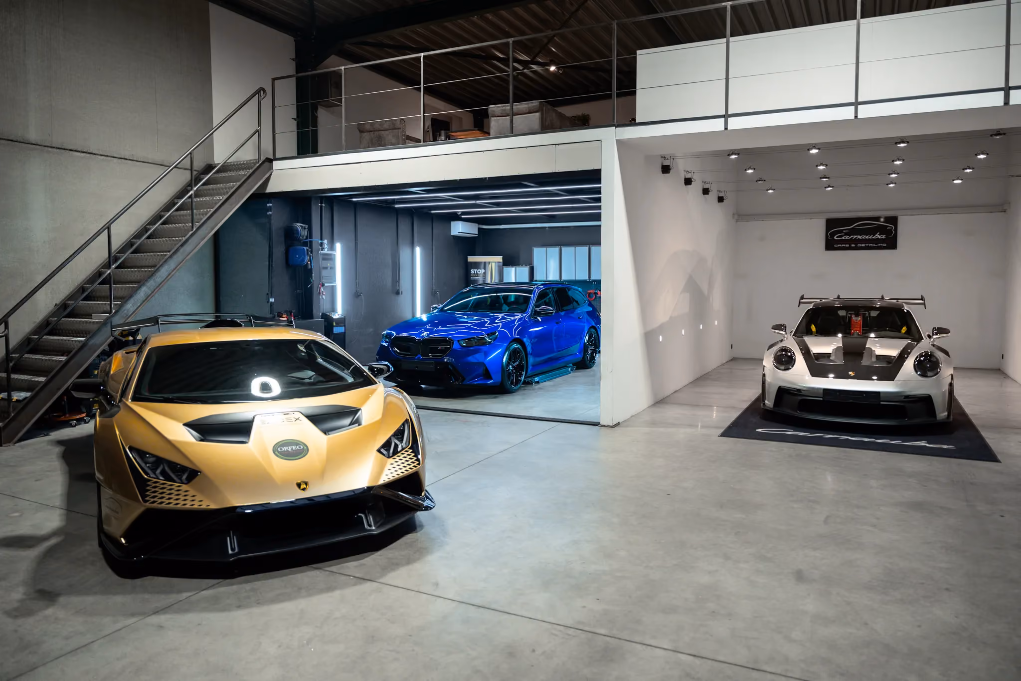 Gouden Lamborghini Huracán, blauwe BMW en witte Porsche racewagen in de werkplaats van Carnauba