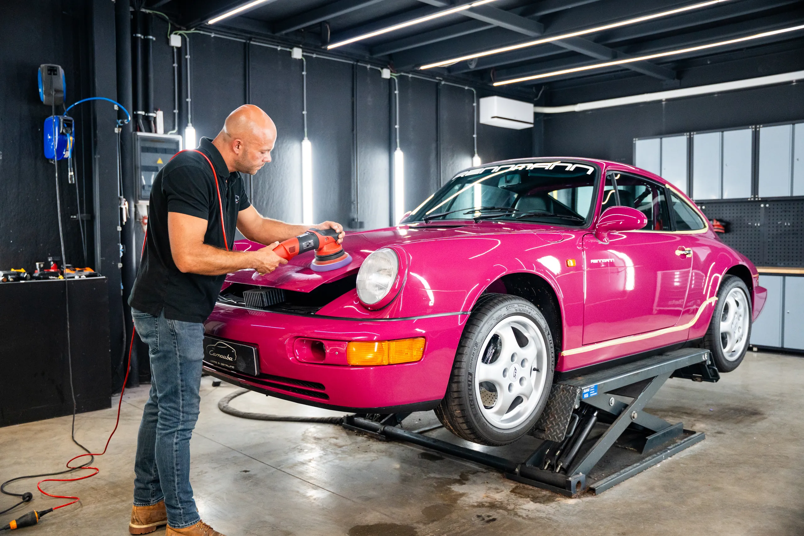Detailer van Carnauba polijst een Porsche 964 op de hefbrug in de werkplaats in Oostkamp