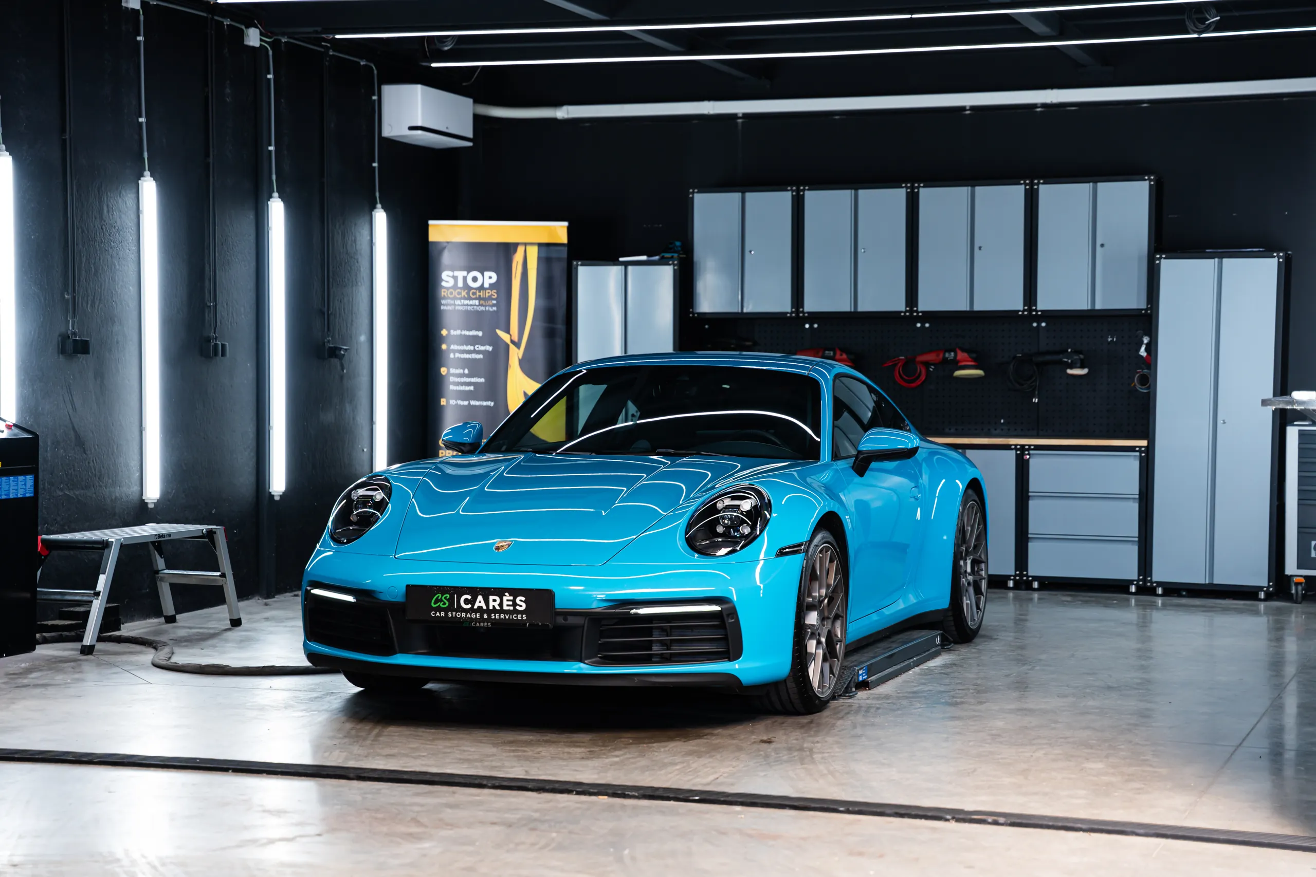 Blauwe Porsche 911 met XPEL paint protection film banner in de werkplaats van Carnauba