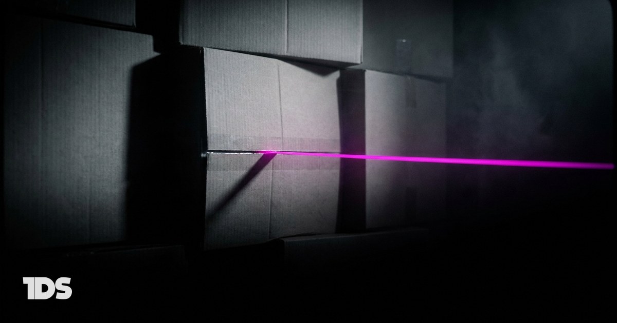 Stacked shipping cartons in the dark with a magenta line of light running out of one seam, representing social media agencies that turn e-commerce content into orders
