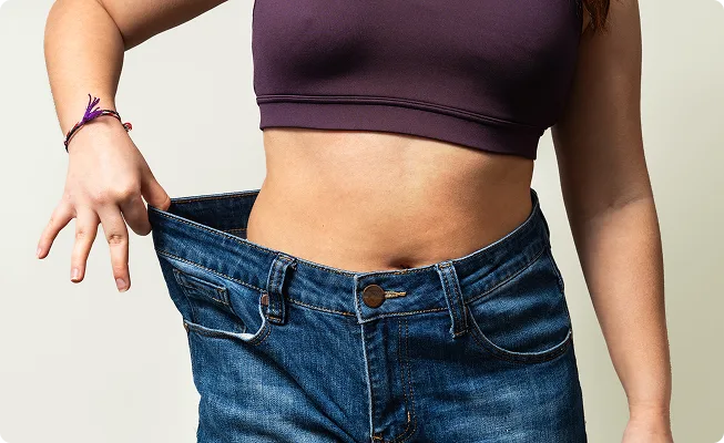 woman stretching loose fitting jeans