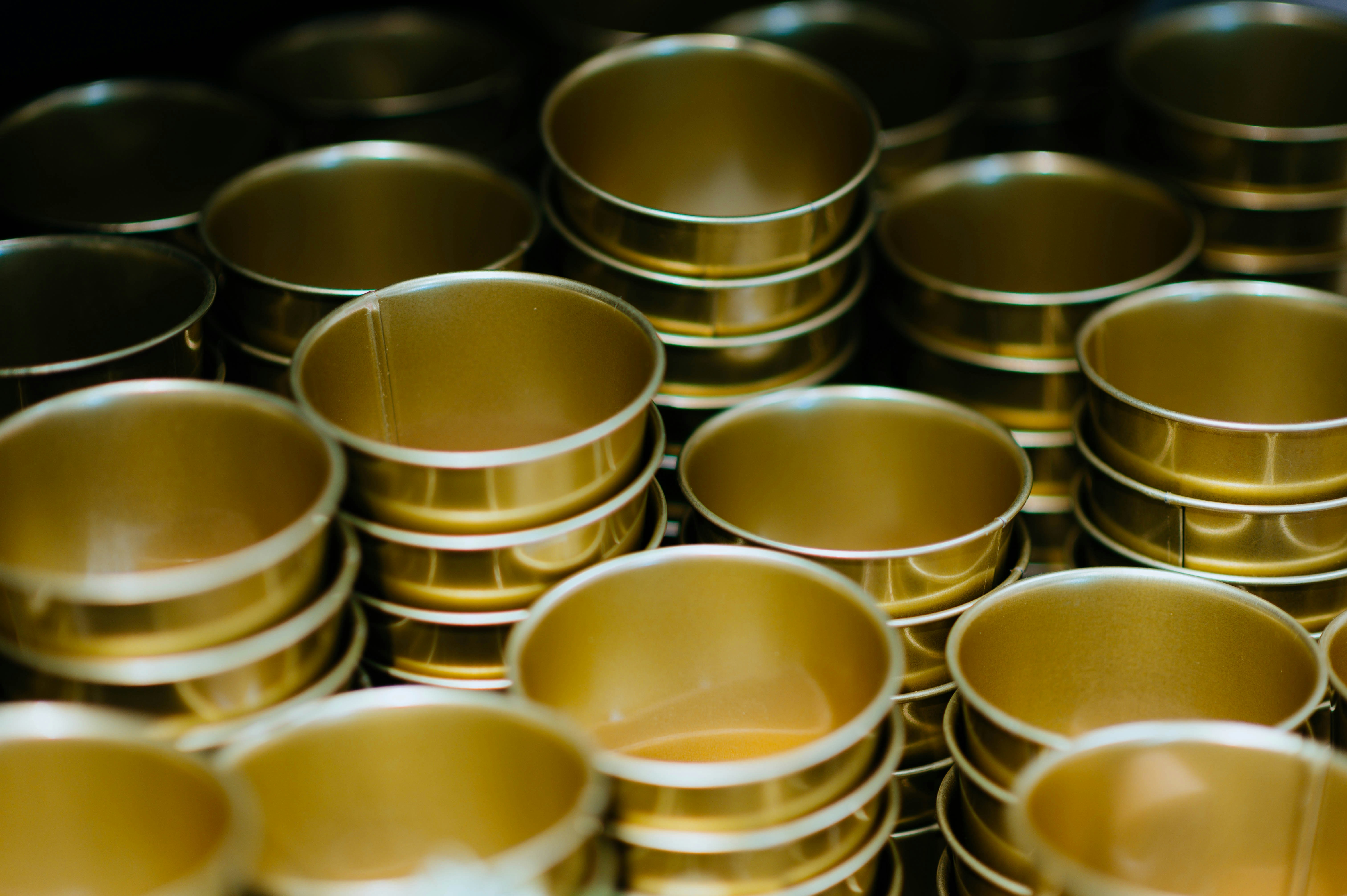 Empty gold aluminum tuna cans stacked and ready for hand-packing during the Hookd processing stage.