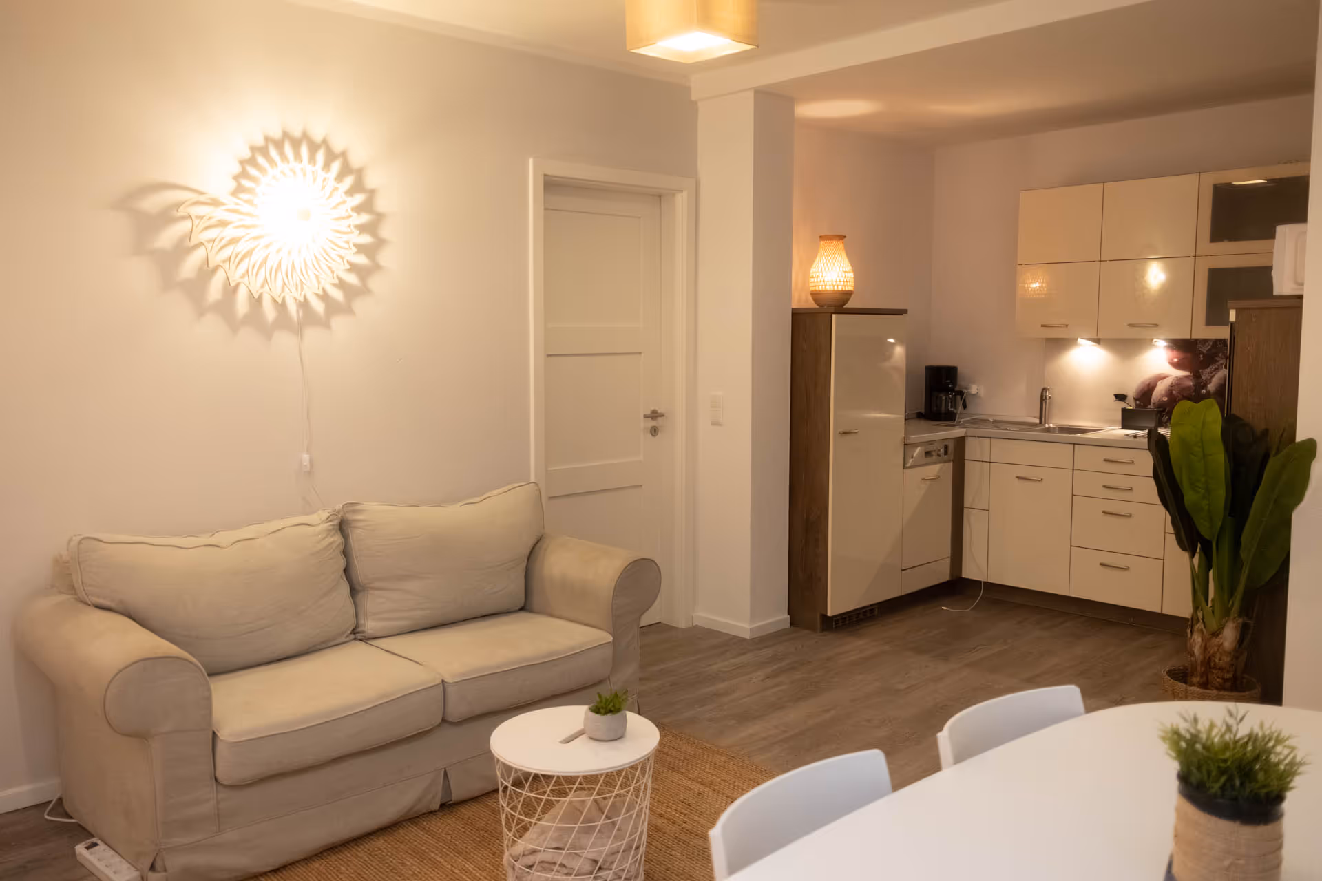 Wohnzimmer mit Sofa, Esstisch und Kuechenzeile