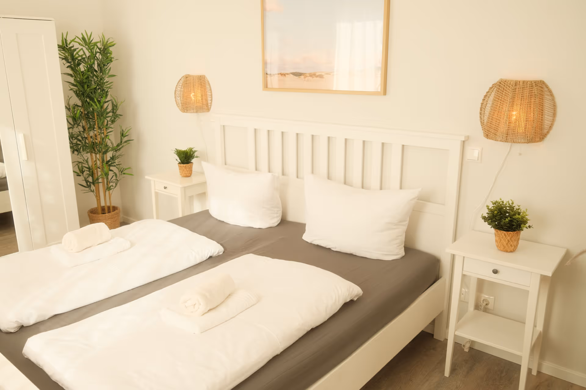 Doppelbett mit weißen Nachttischen und Dekobildern