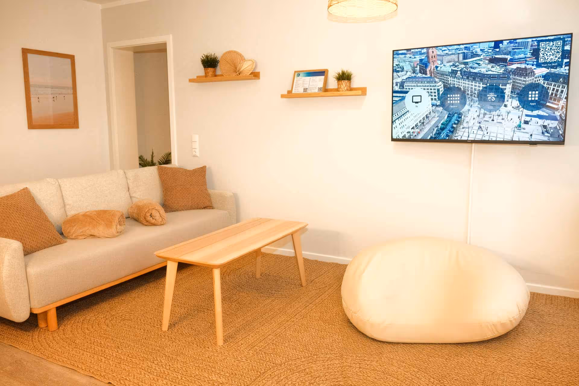 Wandfernseher gegenueber hellgrauem Sofa und Sitzsack