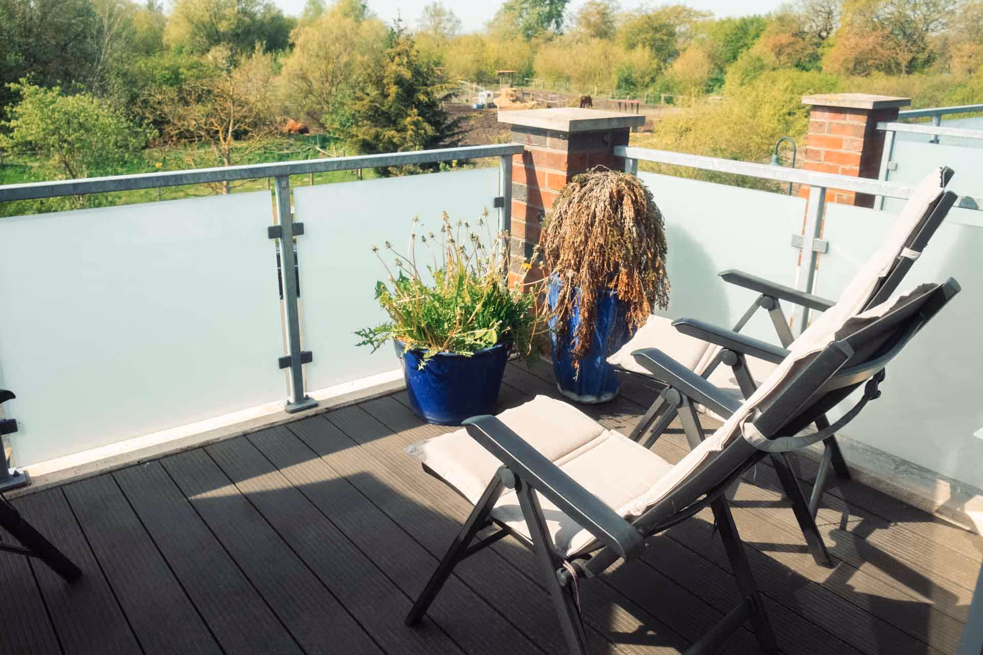 Balkon mit zwei Liegestuehlen und Pflanztöpfen