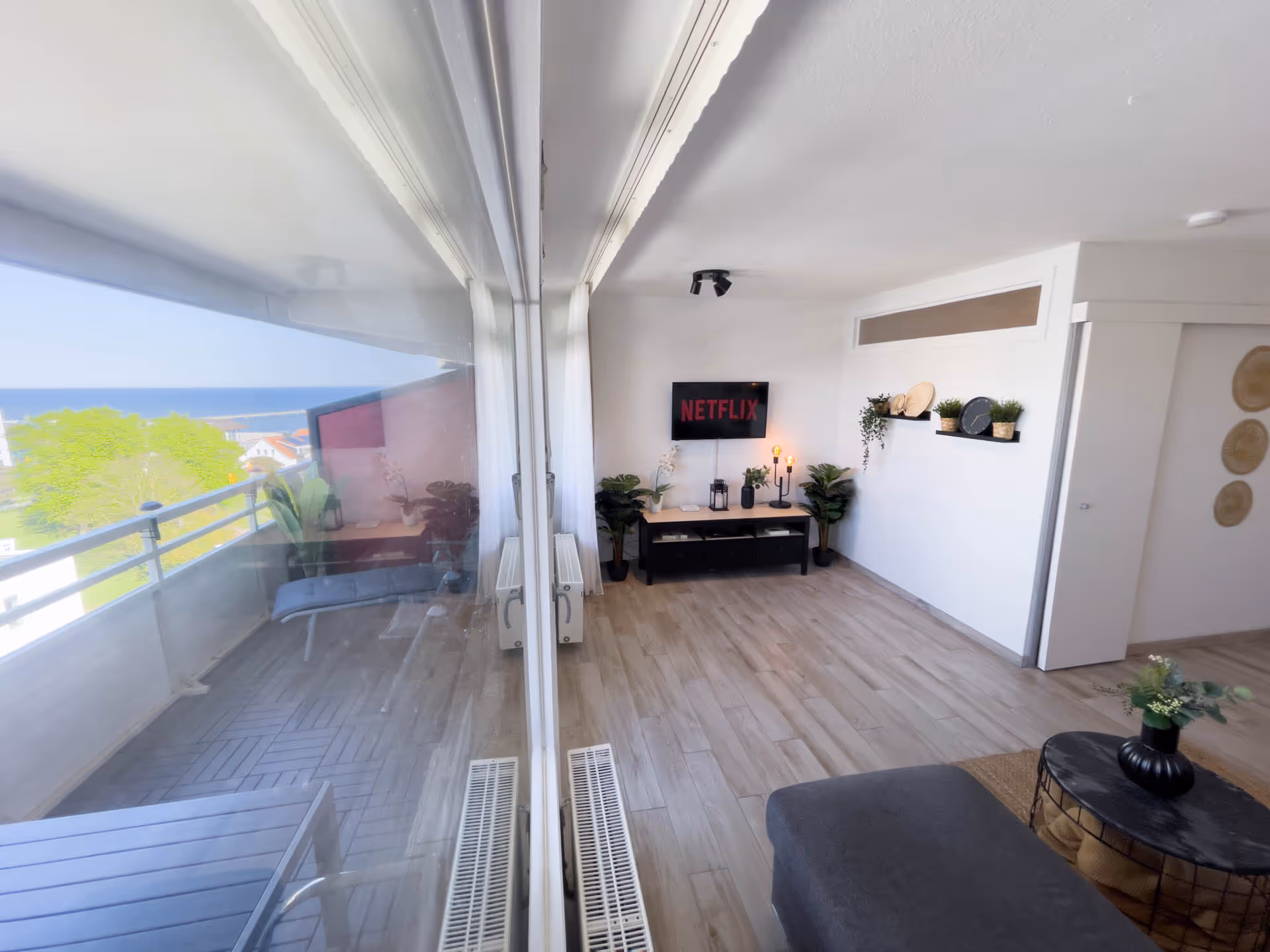 Wohnzimmer mit Balkonblick und Fernseher