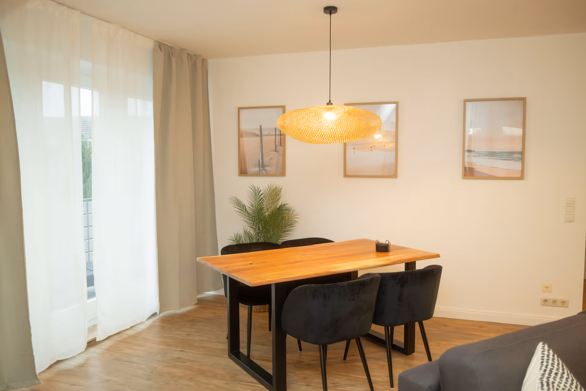 Holztisch mit schwarzen Stuehlen und Wandbildern