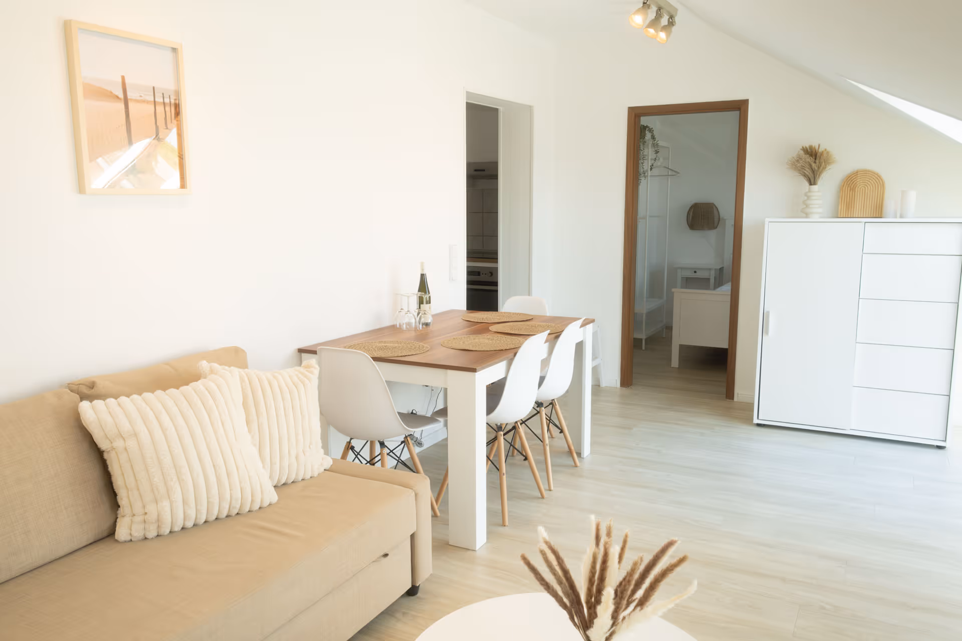 Essbereich mit vier weißen Stuehlen und Sofa