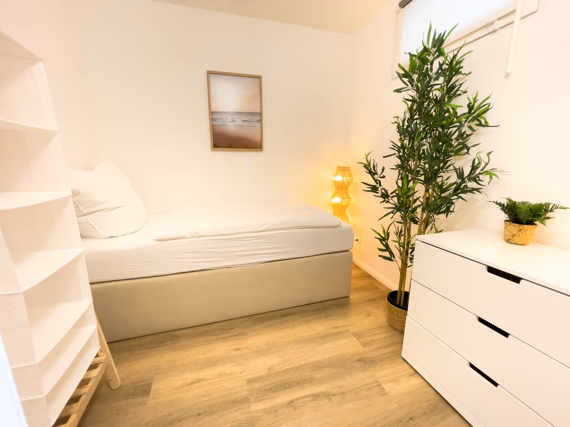 Einzelbett mit Pflanzen und heller Einrichtung