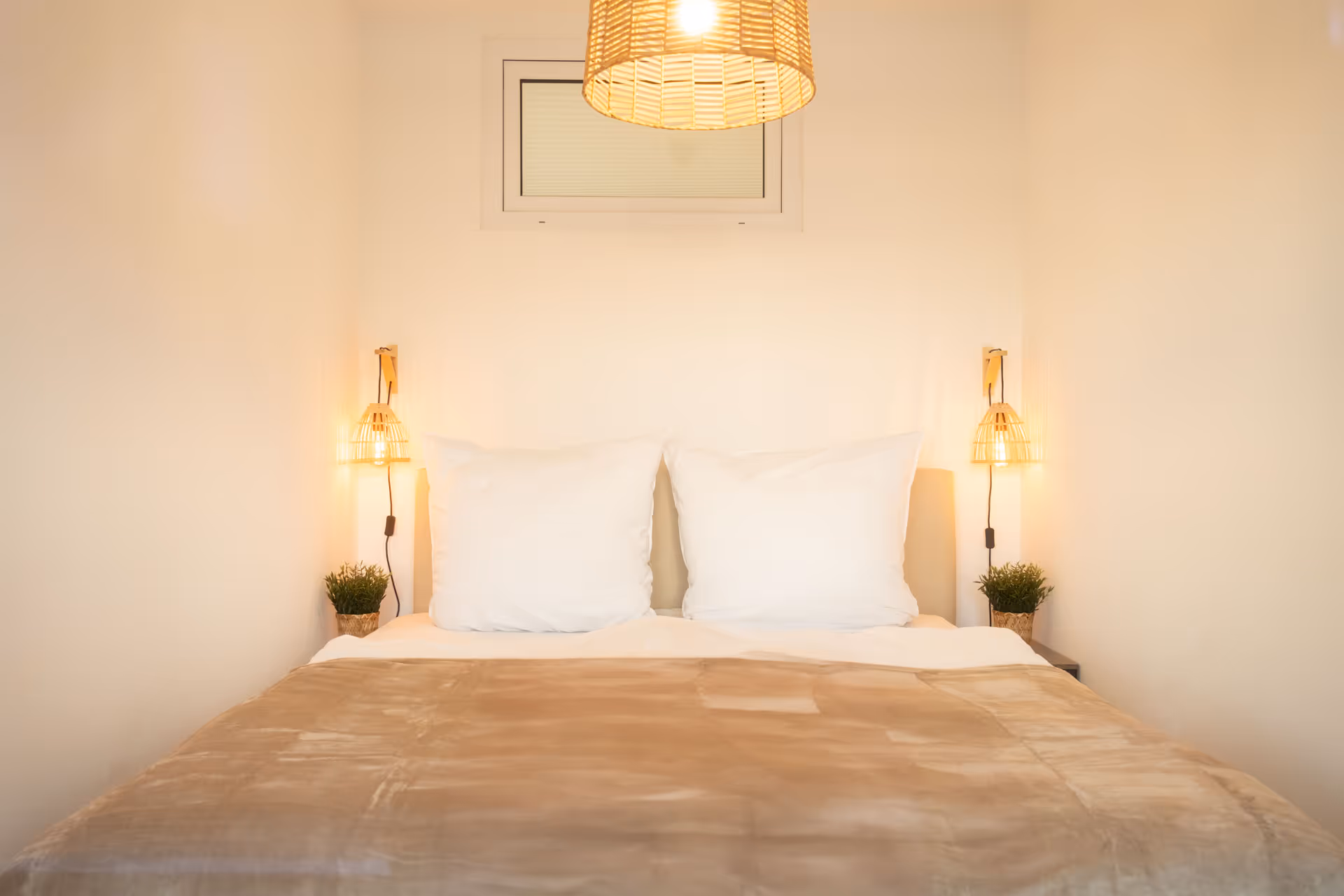 Doppelbett mit Wandlampen und Pflanzen