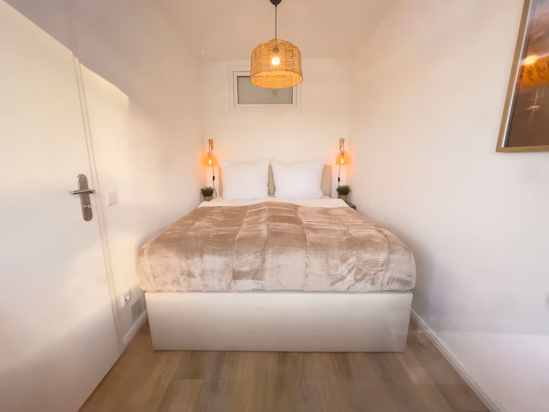 Doppelbett mit Rattanlampen und heller Bettwaesche