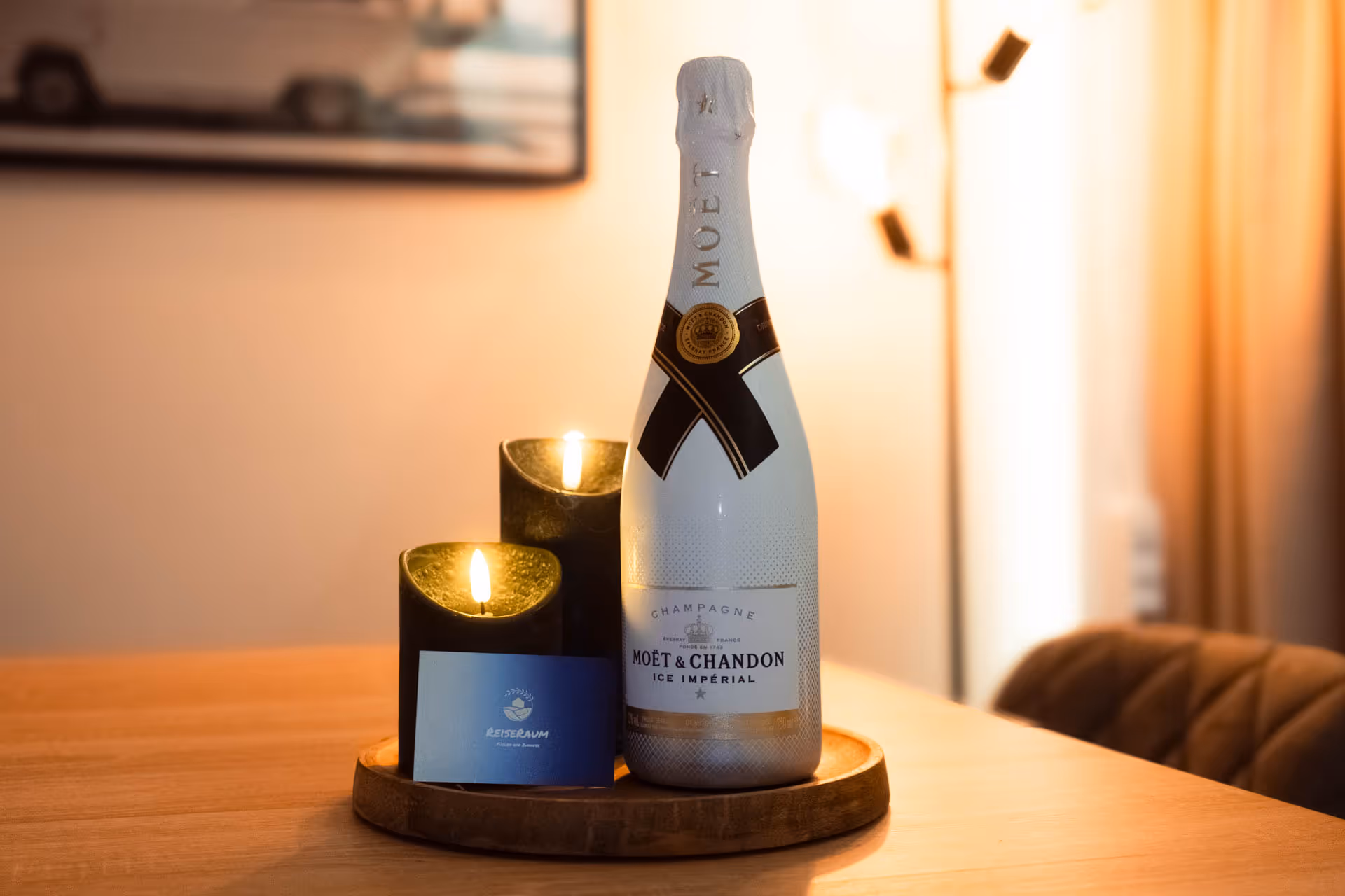 Sektflasche und Kerzen auf Holztablett