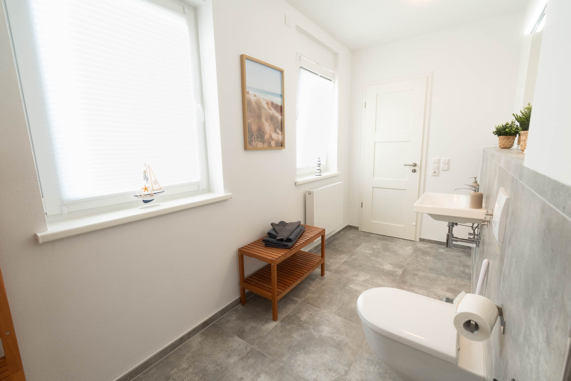 Badezimmer mit Fenster und Holzablage und Bild an der Wand