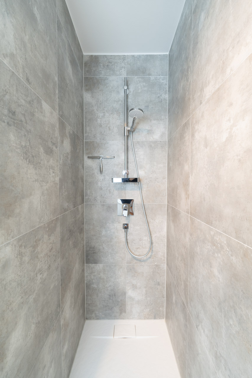 Moderne Dusche mit grauen Fliesen und Handbrause