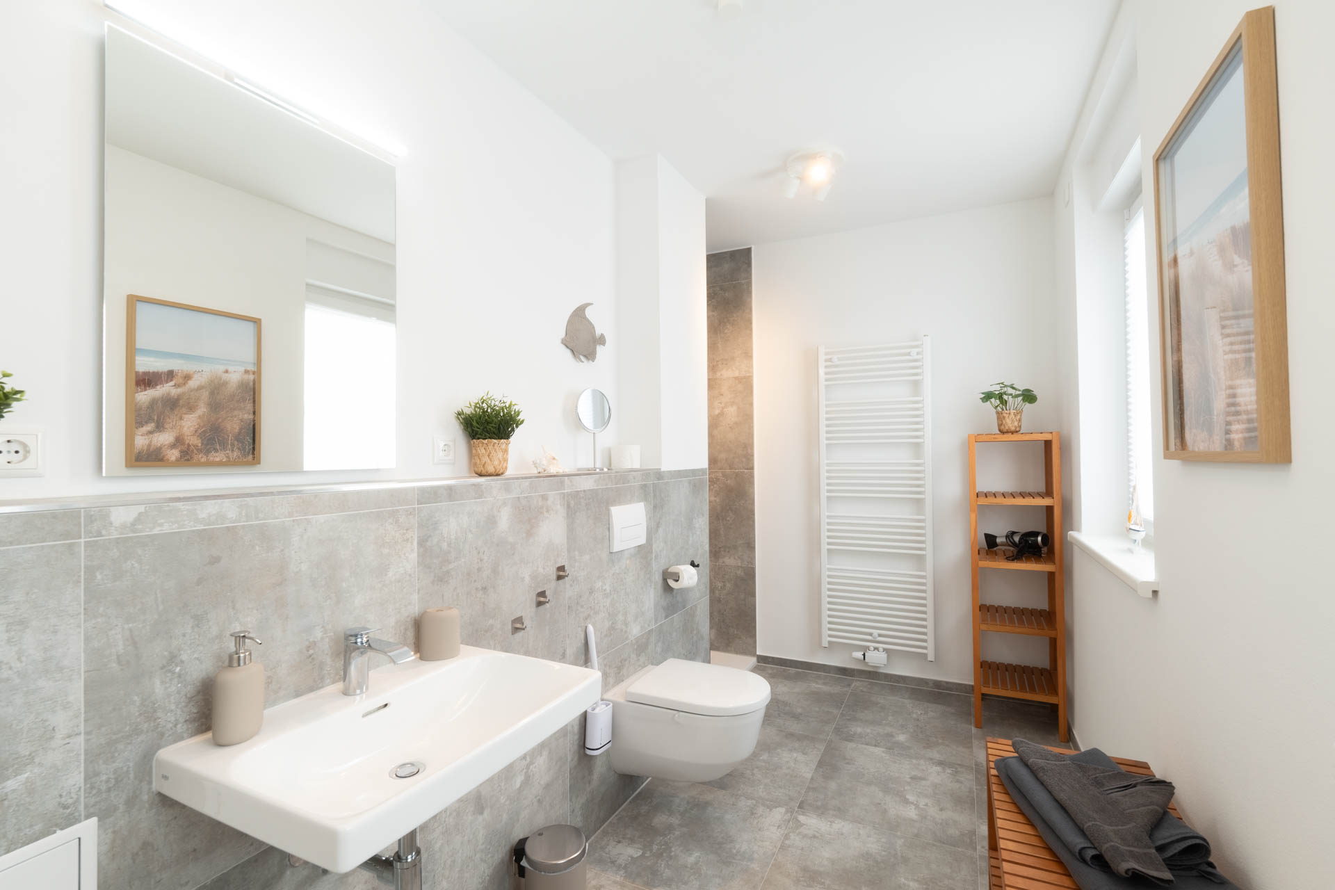 Helles Badezimmer mit Dusche, Waschbecken, Spiegel und Handtuchheizkörper