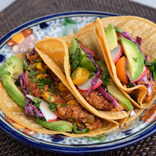 Three quinoa tacos with avocado, radish on a colorfull plate.