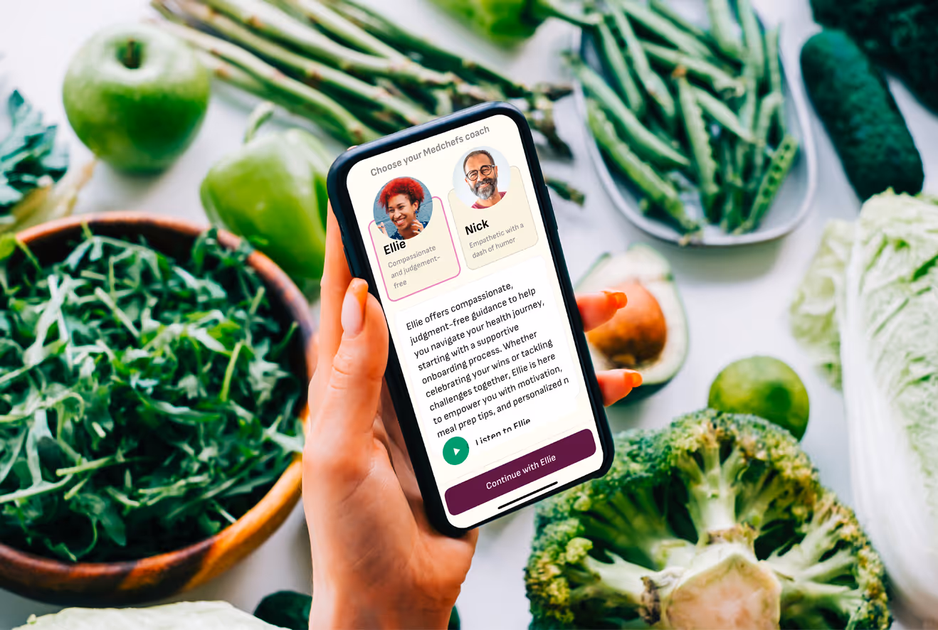 Hand holding a phone with images of AI coaches. Green vegetables in the background