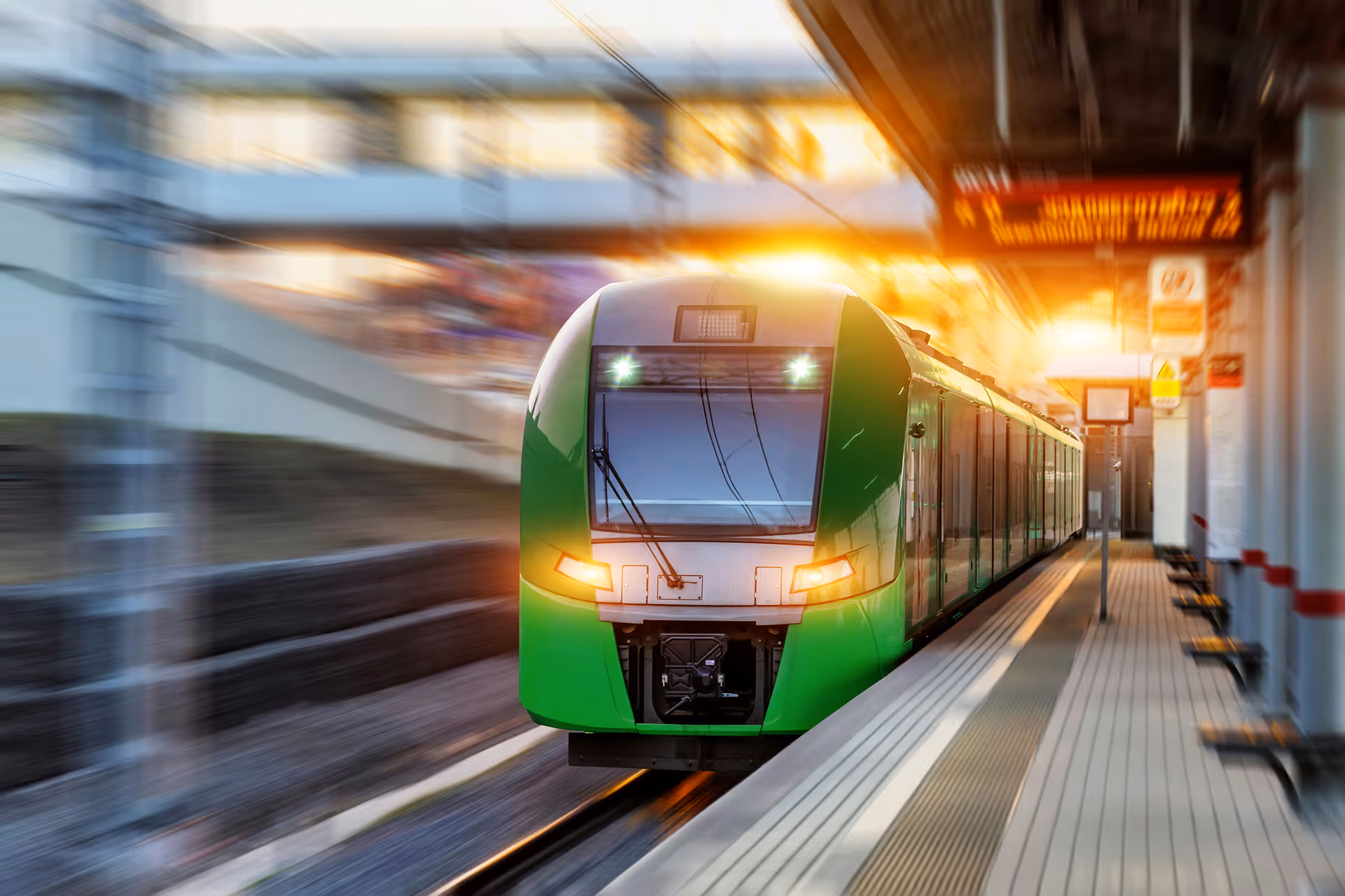 Modern green passenger train arriving at a station, representing Wileo’s rail and transport engineering expertise