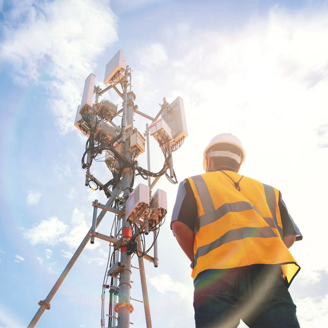 Engineer in safety gear inspecting telecommunications tower, representing Wileo’s communications systems expertise