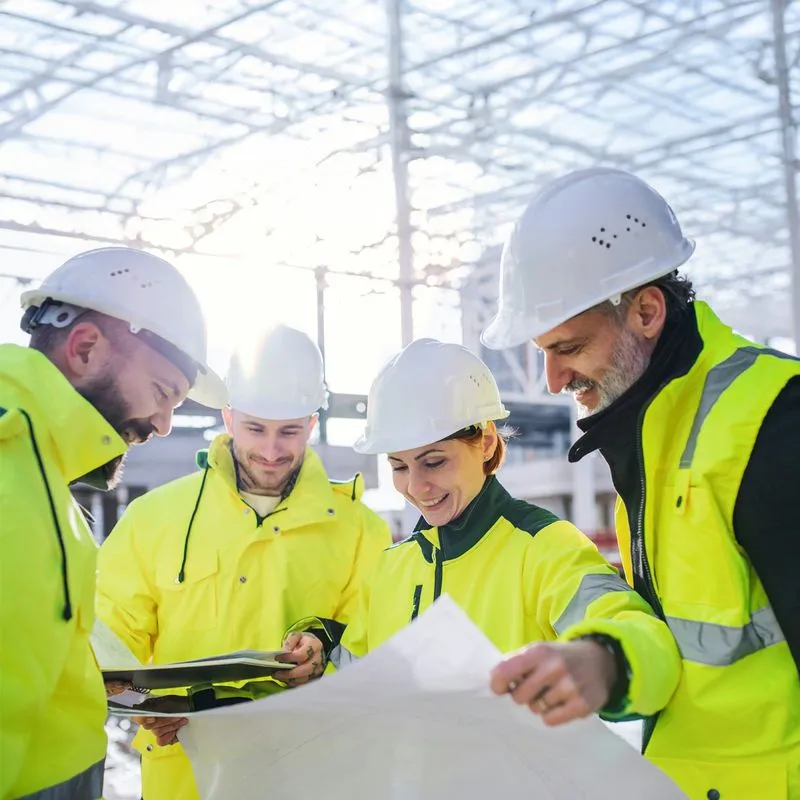 Team of engineers in safety gear reviewing blueprints on site, representing Wileo’s collaborative project delivery expertise