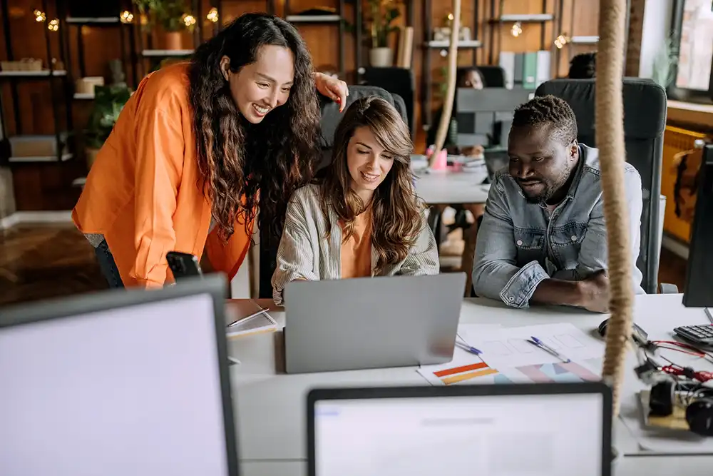 Three publishing professionals collaborating together over a laptop.