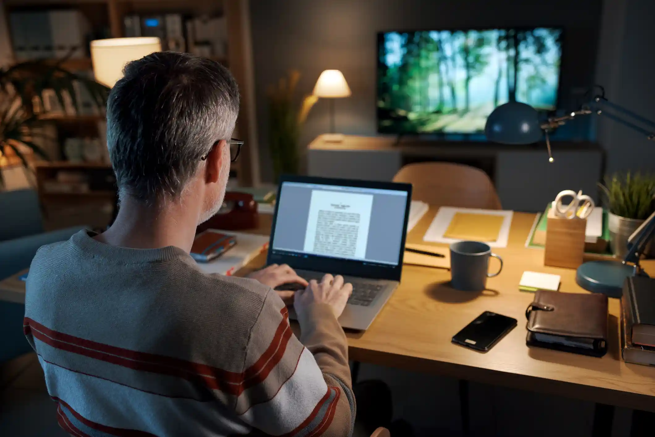 A man typing on a laptop in his home office.