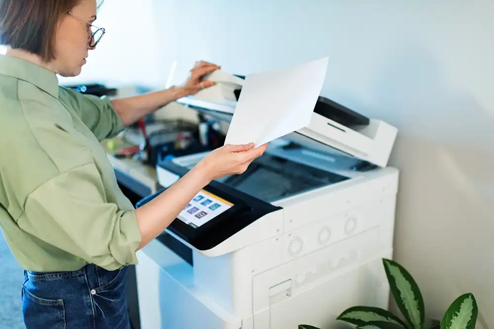 A woman inspecting a copy at a photocopier.