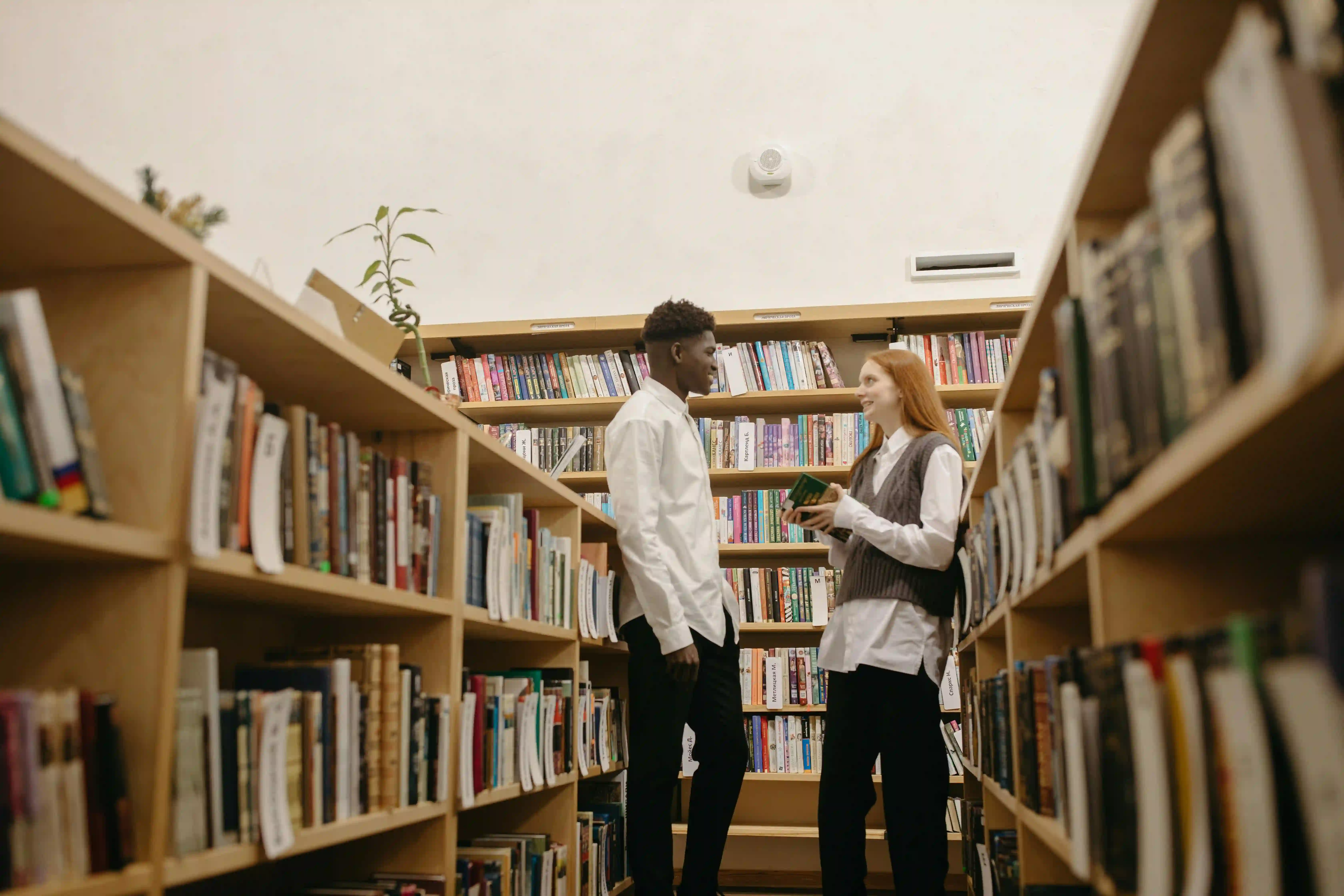 A man and a woman talking to each other in a public library.