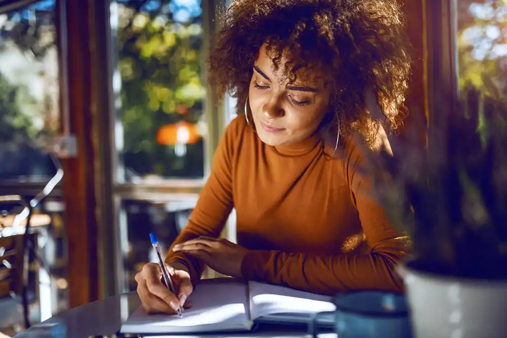 A female creator writing in a cafe.