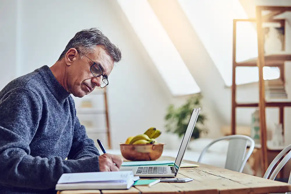 A male creator working and writing at a home office.