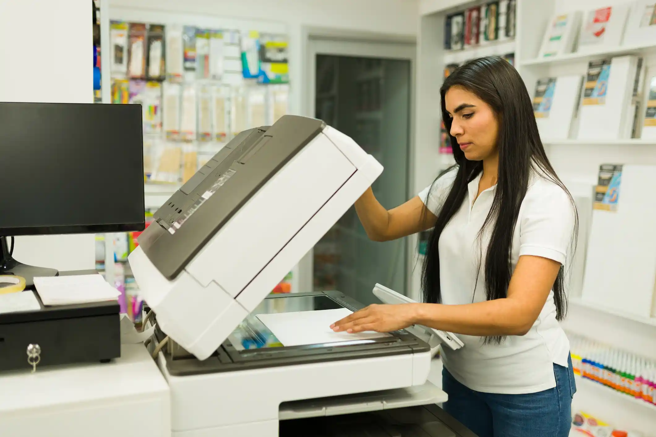 A copyshop employees making copies at a photocopier.