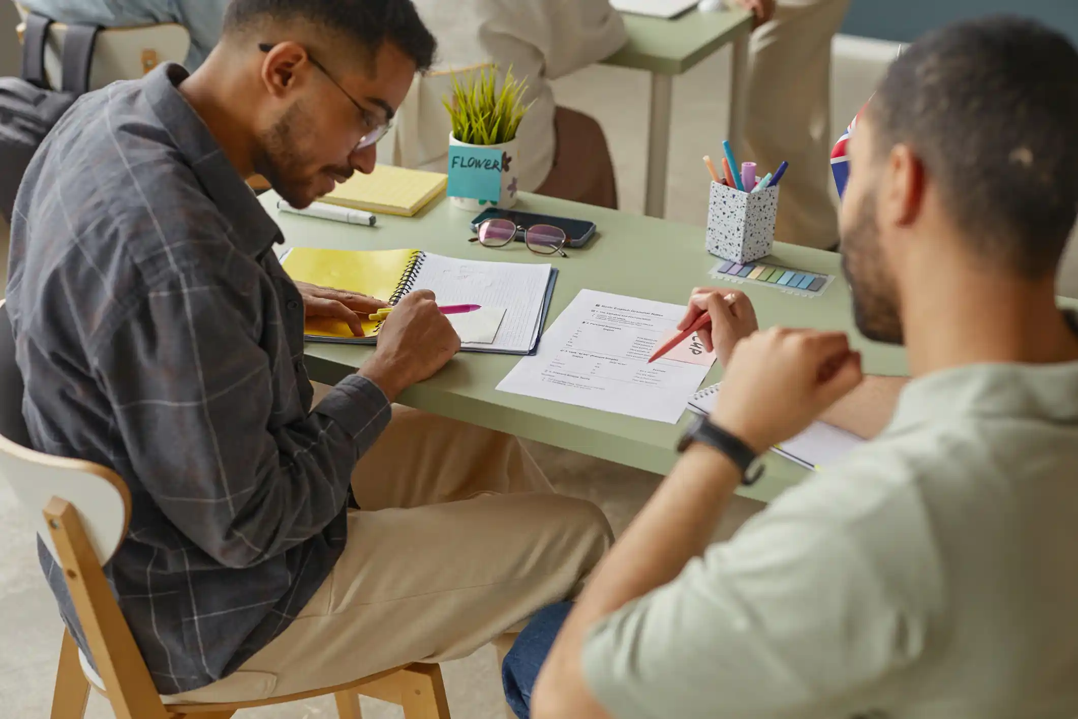 Two male students work together at a desk in a classroom.