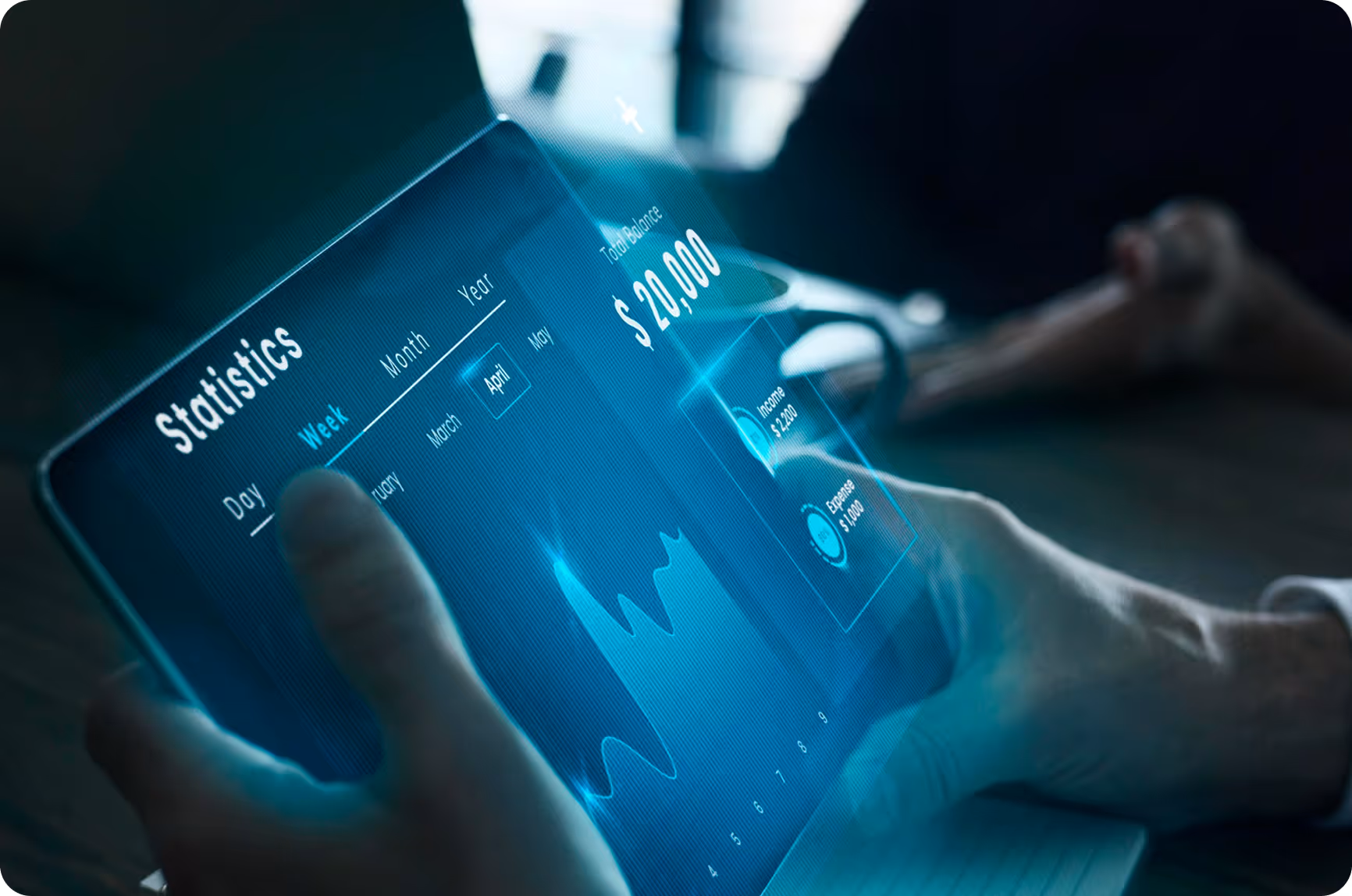 Person interacting with a transparent tablet displaying financial statistics including total balance, income, expenses, and a line graph.