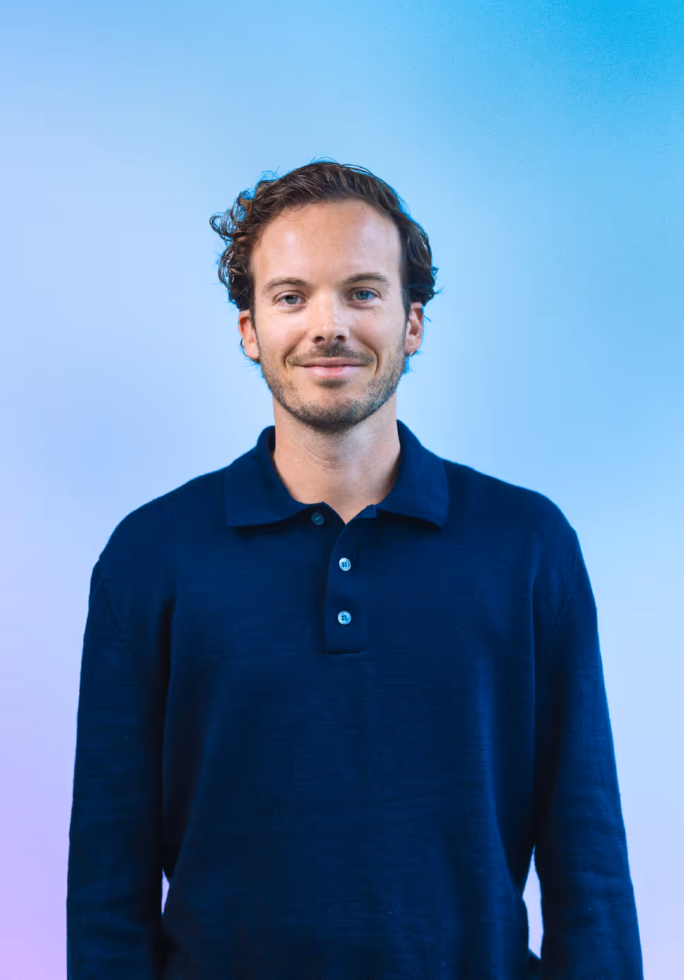 Frontal picture of MP Yannis in front of a blue background.