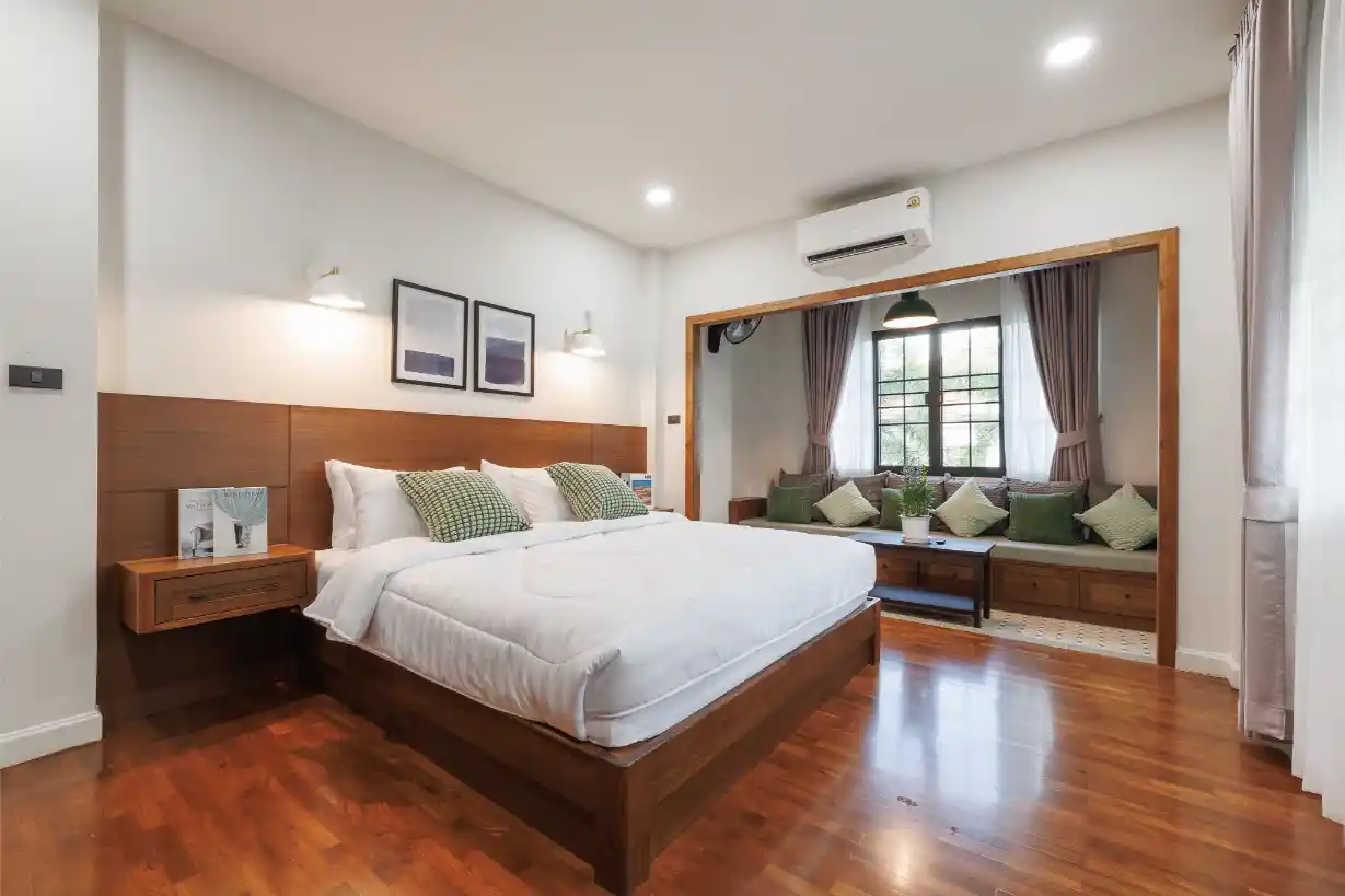 Spacious master bedroom with polished teak floors and an attached reading nook with a window.