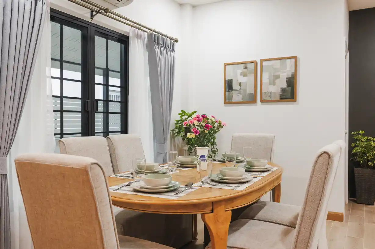 The bright dining area featuring a wooden table for six, set for a meal by a large window.