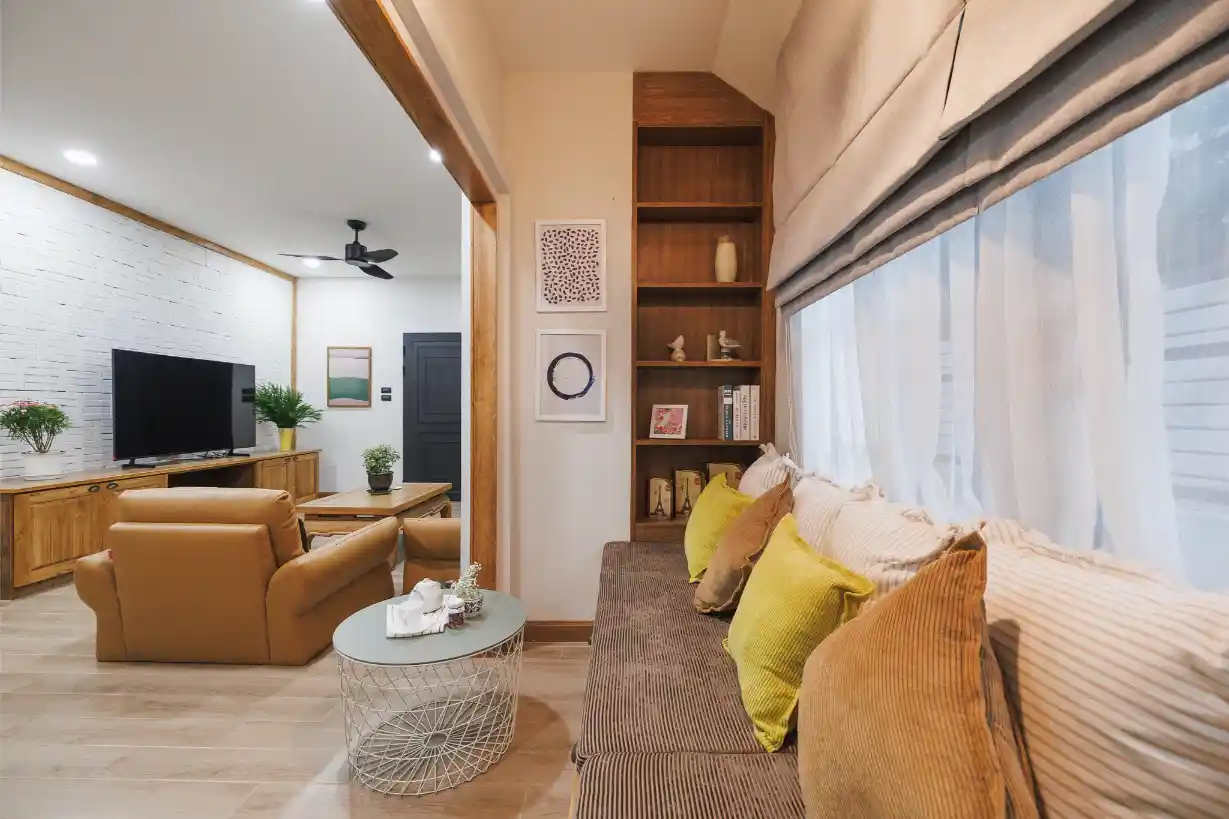A cozy reception area with a window seat and bookshelf, opening into the main living room.