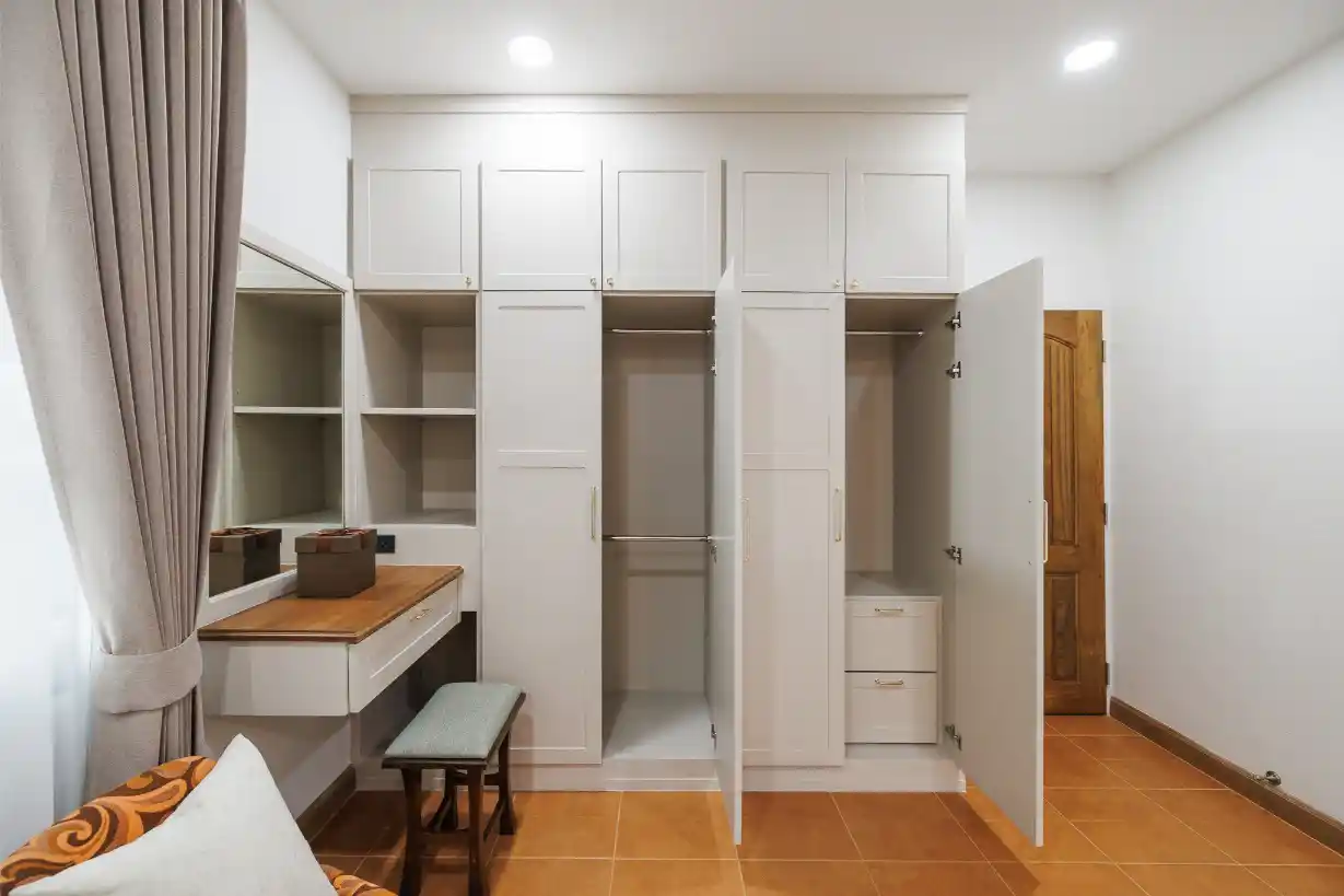 Bedroom's built-in white wardrobe with hanging space, shelves, and an integrated vanity table.