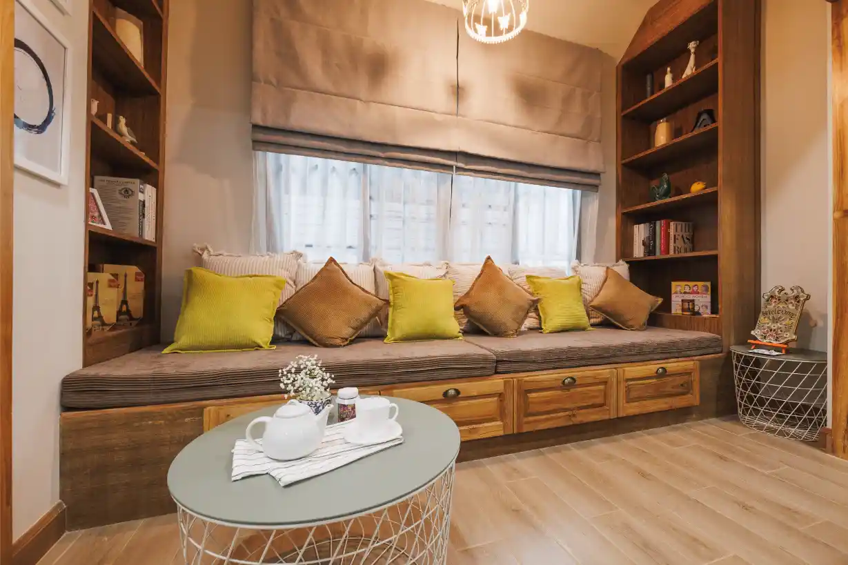 A cozy reading nook with a built-in window seat, storage drawers, and flanking bookshelves.