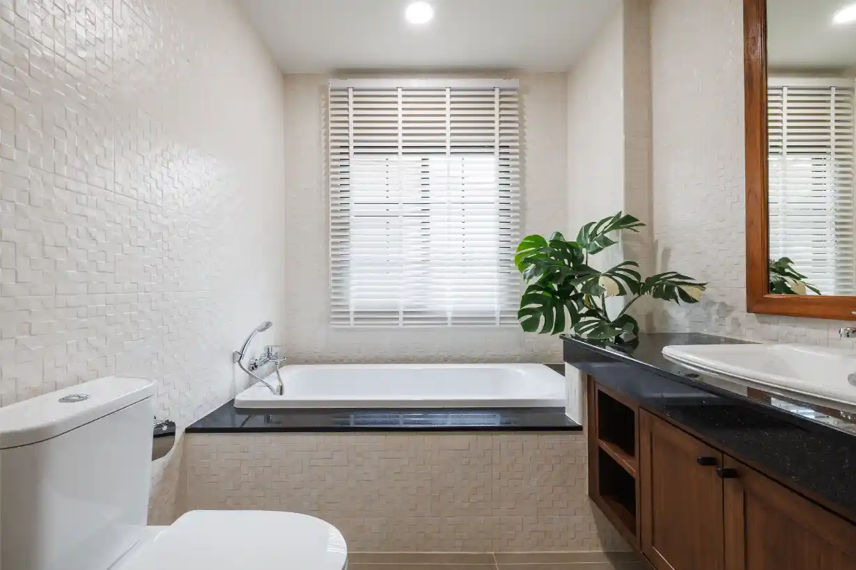 The master bathroom featuring a full-size bathtub, wood vanity, and textured white tile walls