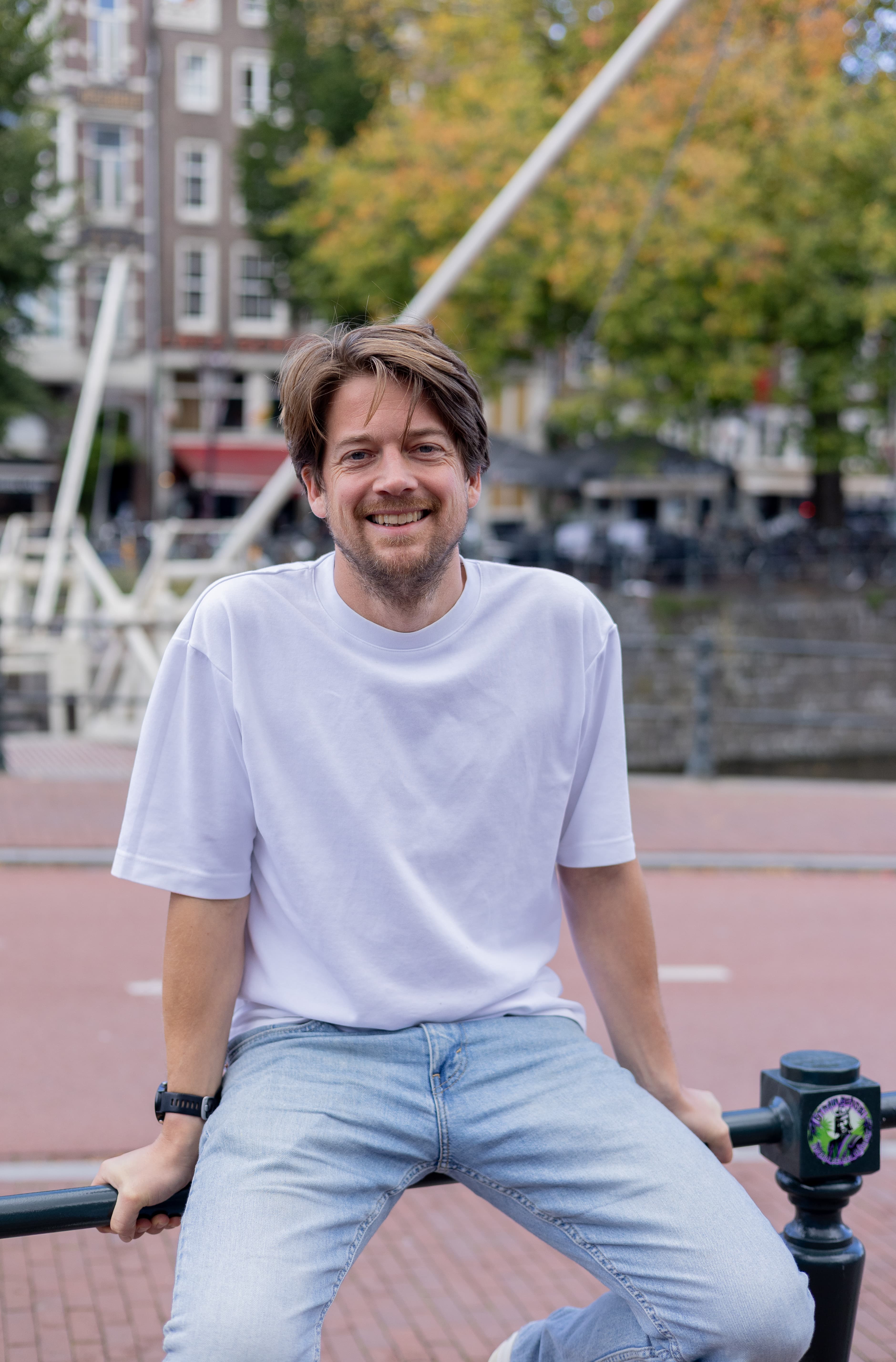 Robert-Jan Burger, oprichter van Groeileaders zit op een hek aan de Amsterdamse gracht.