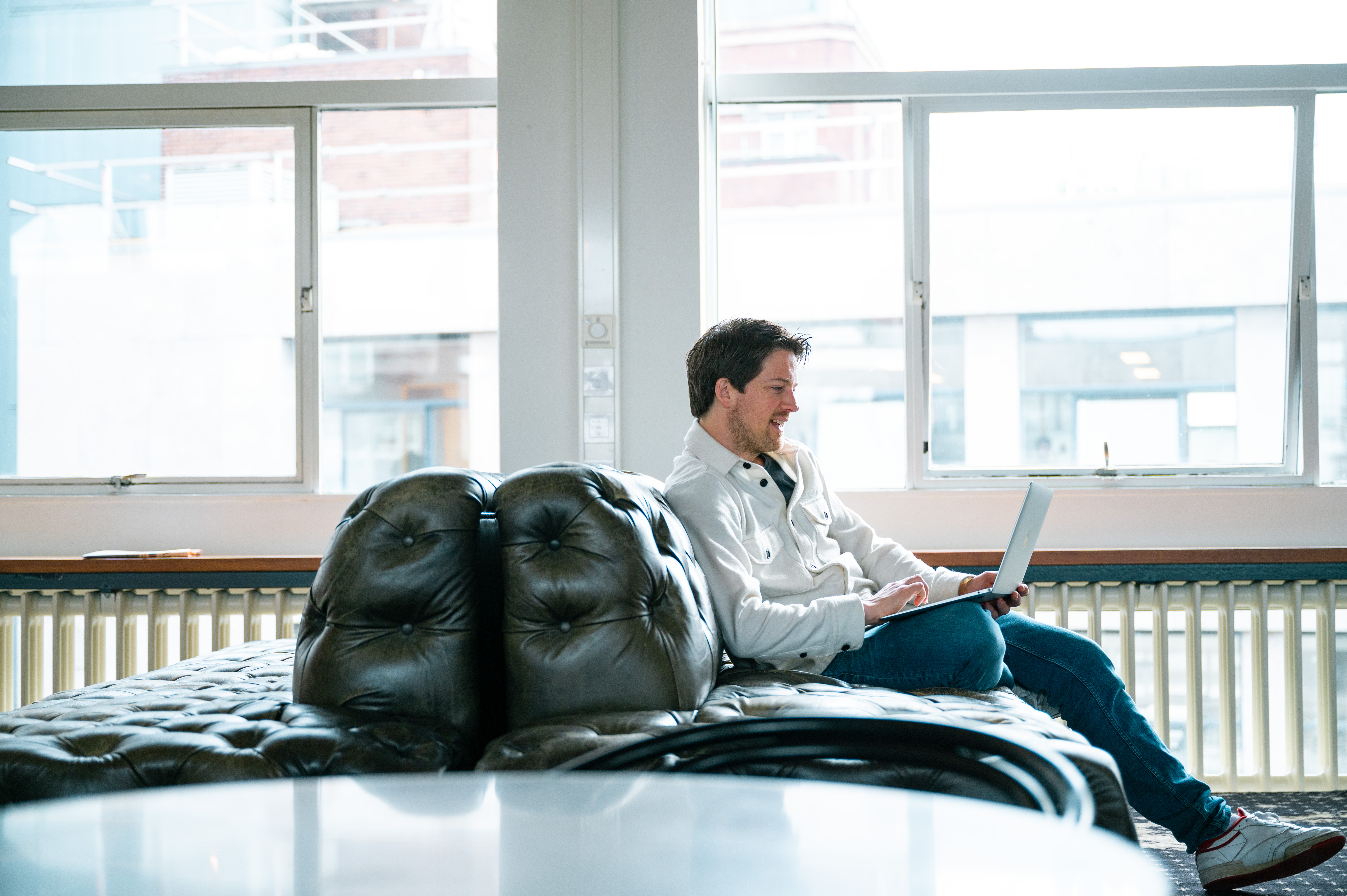 Man zit op bank met laptop