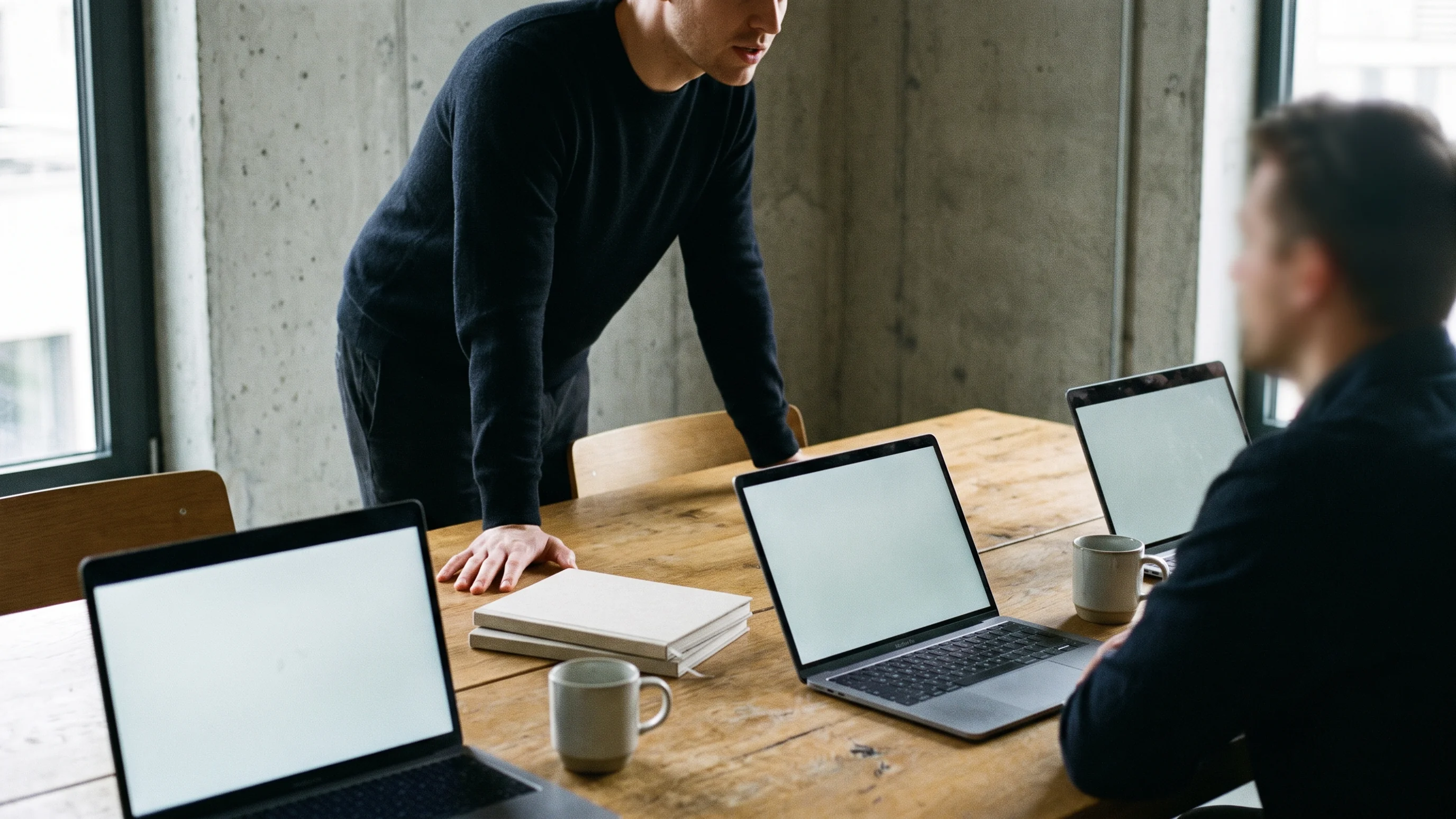 Twee collega's bespreken AI-strategie aan een eikenhouten vergadertafel met laptops en notitieboeken