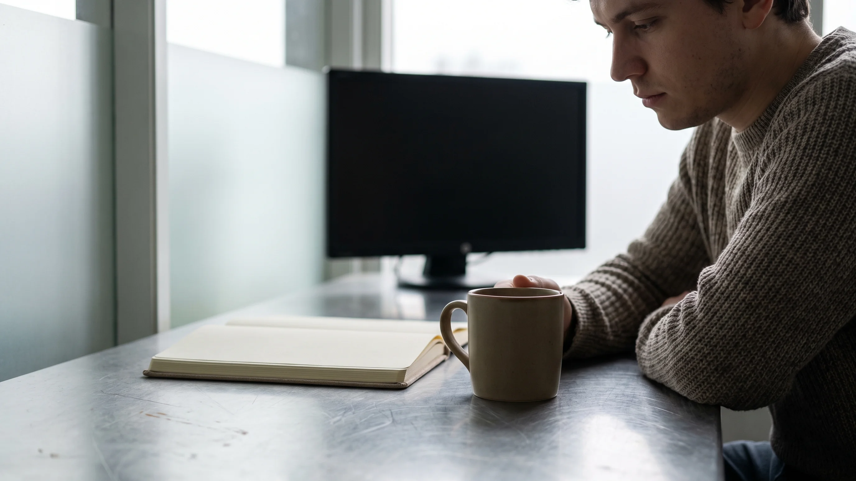 Persoon op kantoor overweegt go no-go beslissing bij AI-pilotevaluatie met notitieboek en koffie