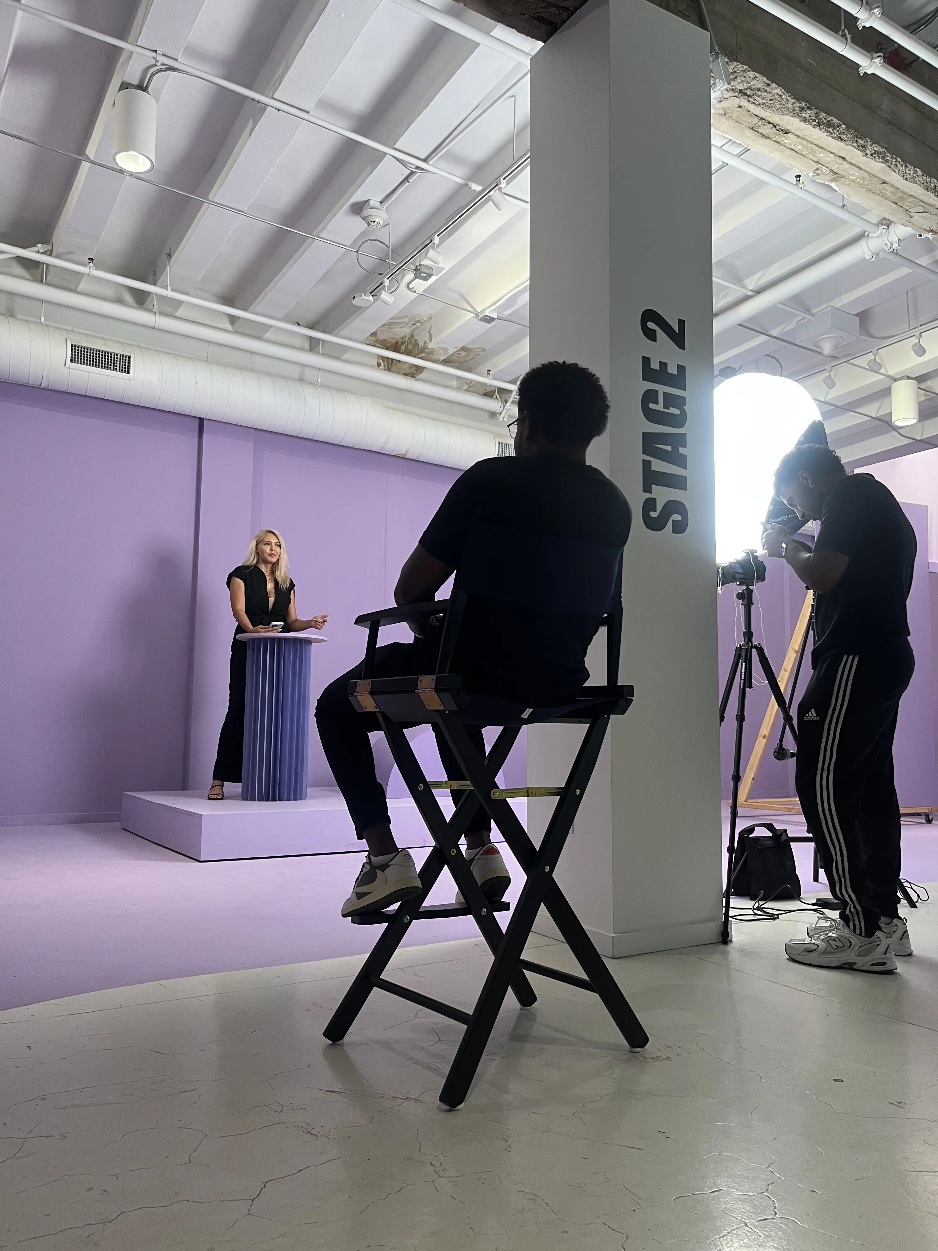 A behind-the-scenes photo of Kaila Uli being filmed while talking behind a purple podium 