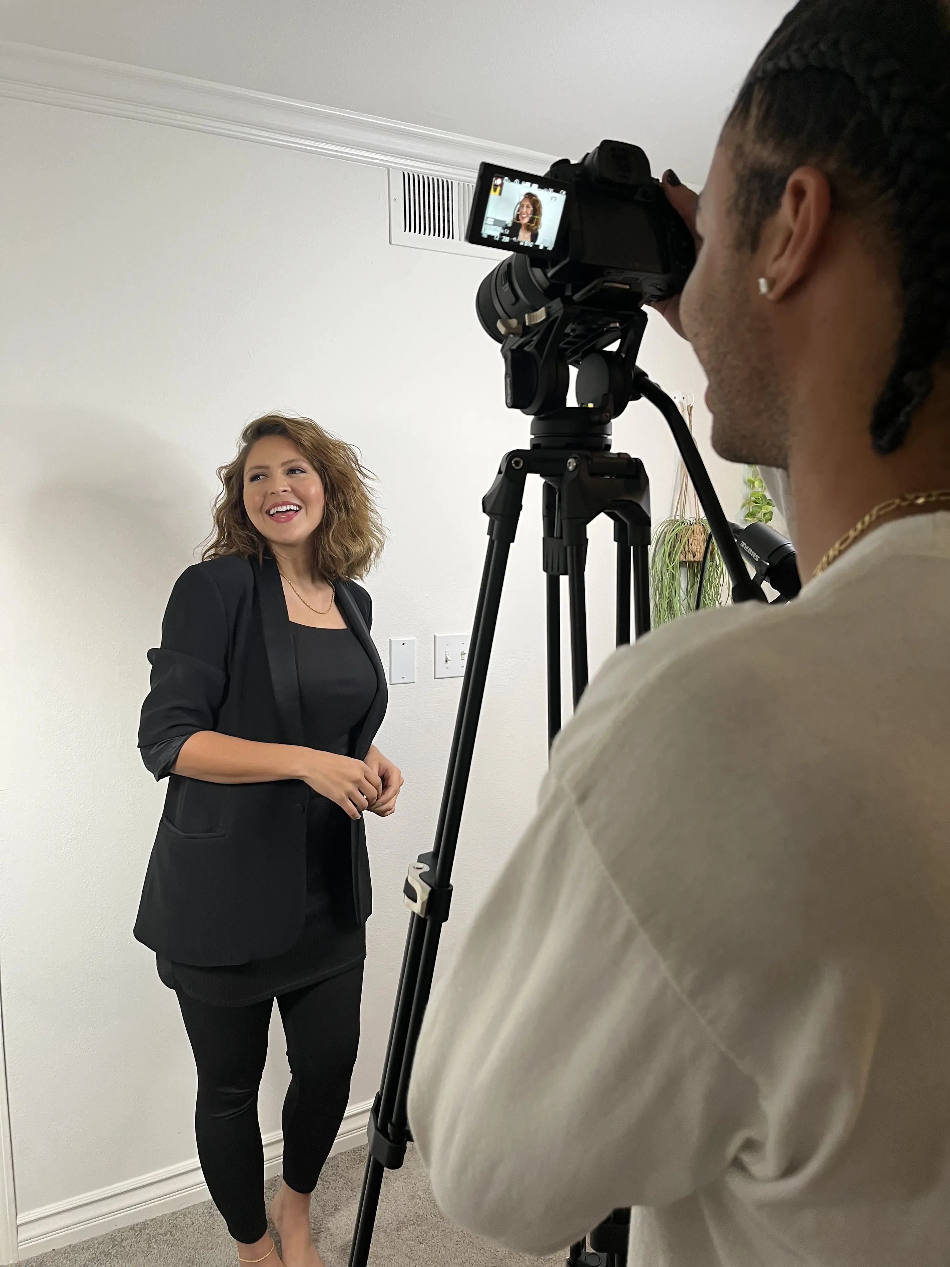 A candid behind the scenes photo of Kaila Uli as she gets her photo taken in front of a bright white wall.