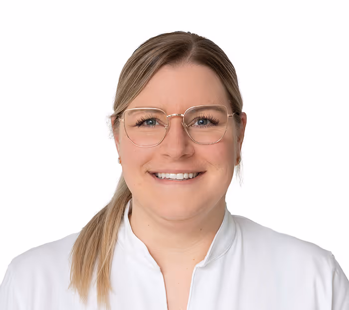 Porträt einer lächelnden Frau mit blonden Haaren, die einen Pferdeschwanz trägt und eine weiße Bluse sowie eine Brille mit dünnem goldfarbenem Rahmen trägt.